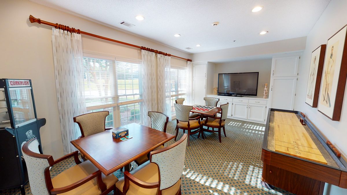 A cozy living room with dining tables, chairs, and a TV.