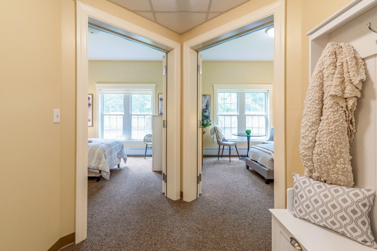 A view of two adjacent bedrooms with large windows letting in natural light.