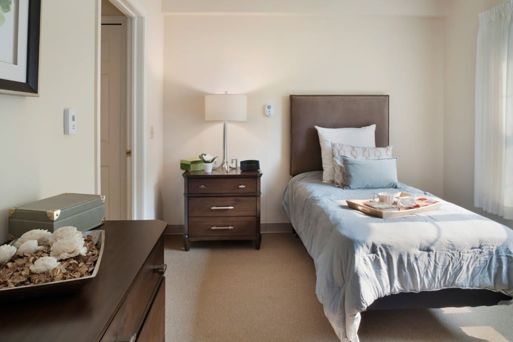 A cozy bedroom with a single bed and a nightstand adorned with a lamp.