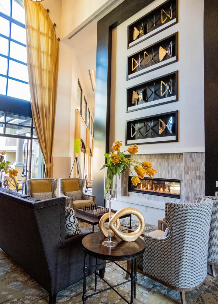 A modern living room with a luxurious seating area, featuring a fireplace and contemporary artwork.