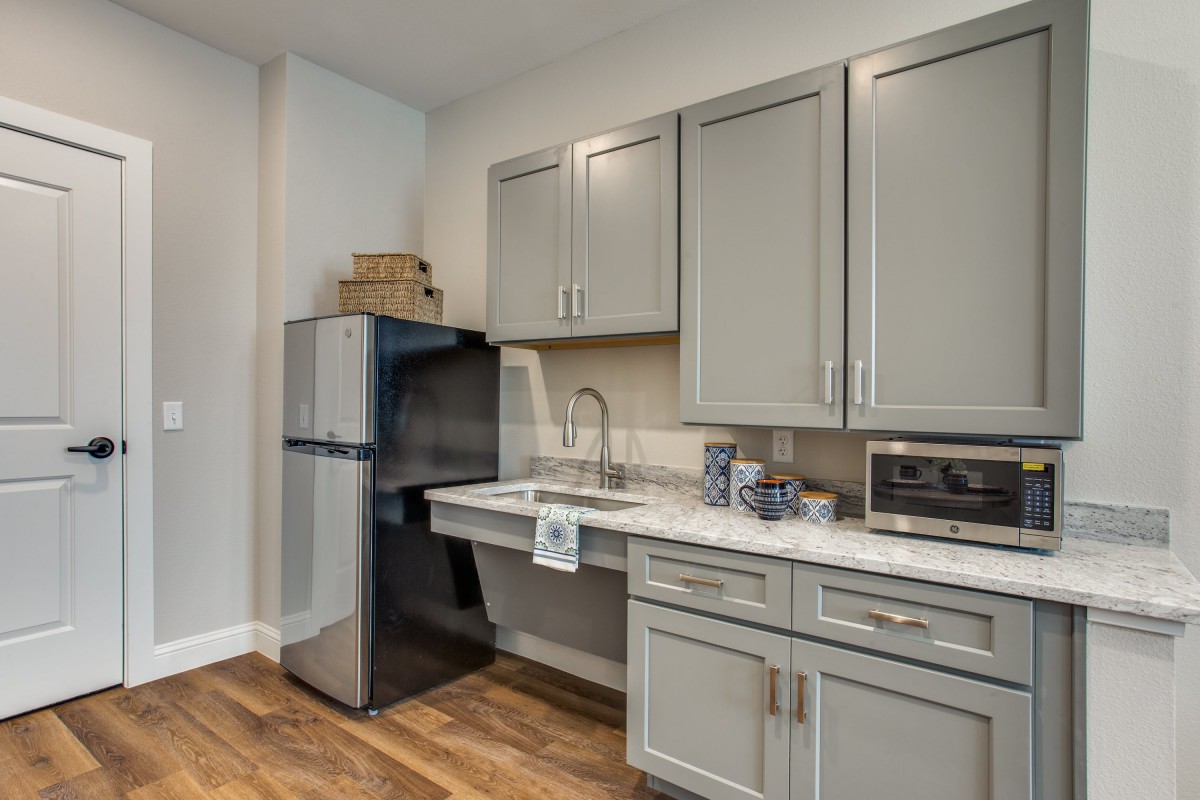 A modern kitchen with gray cabinets, a refrigerator, and a sink.