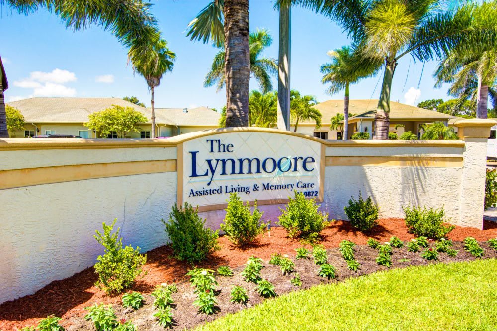 The Lynmoore Assisted Living & Memory Care sign surrounded by landscaped greenery and palm trees.