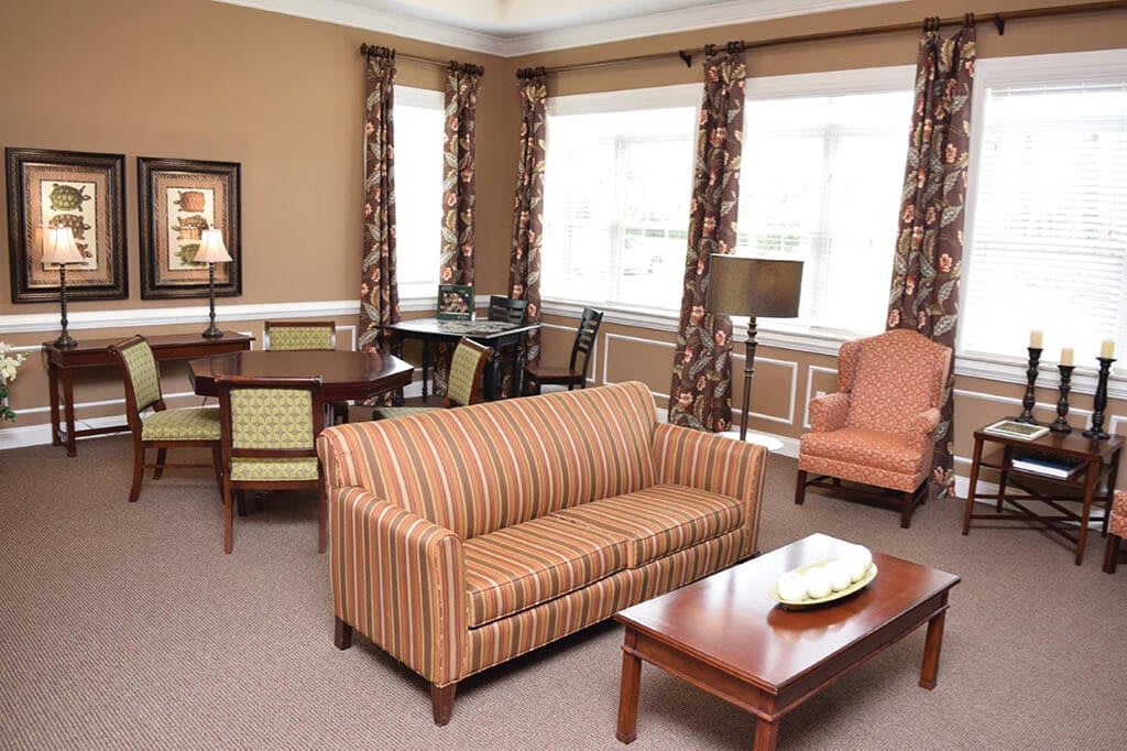 A cozy living room with a striped sofa, a coffee table, and chairs by the windows.