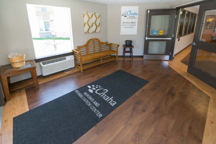 A clean and welcoming lobby area featuring a bench, floor mat, and air conditioner.