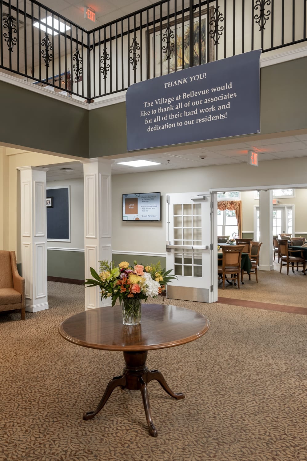A welcoming lobby area with a decorative floral arrangement on a round table and visible seating areas in the background.