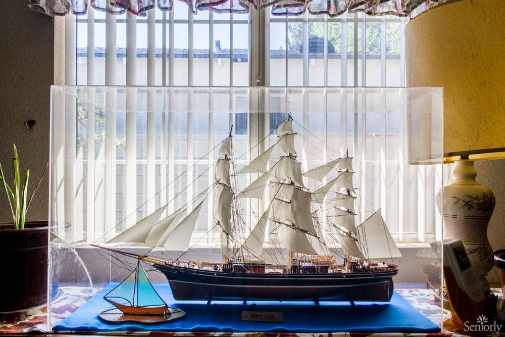 A detailed model of a sailing ship displayed indoors near a window.