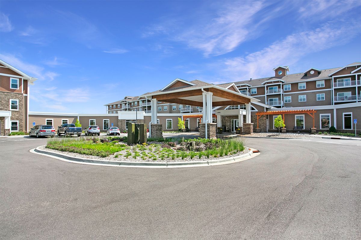 A modern hotel building with a landscaped driveway and clear blue skies.