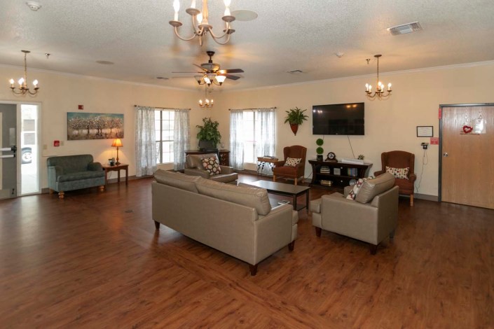 A spacious living room with elegant furnishings and decor, featuring comfortable sofas, armchairs, a coffee table, and a mounted TV.