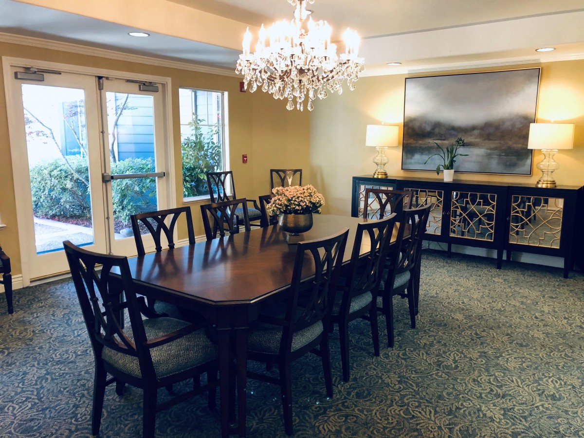 A beautifully decorated dining room with a large table, elegant chandelier, and stylish artwork on the wall.