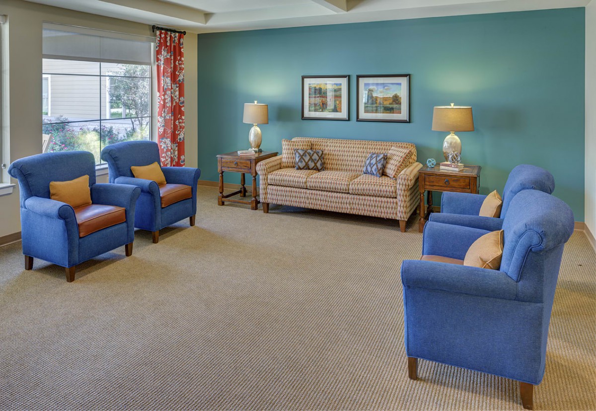 A cozy living room featuring a striped sofa, blue armchairs, and decorative table lamps.