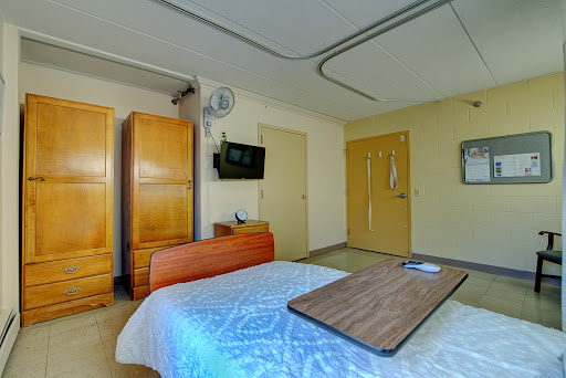 A well-furnished hospital room featuring a bed, wardrobe, and television.