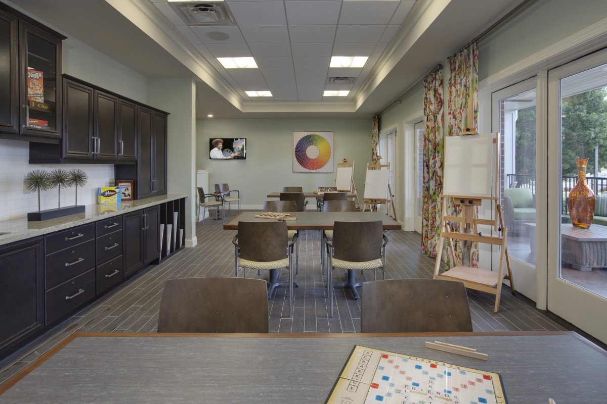 A spacious art studio set up with tables, chairs, and easels, featuring bright lighting and modern decor.