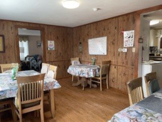 A cozy dining area with wood paneling and floral tablecloths.