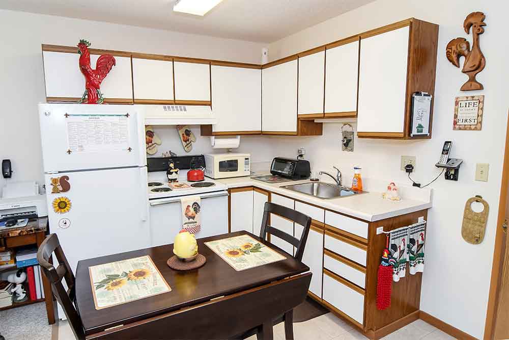 A cozy kitchen with white cabinets, a small dining table, and various appliances.