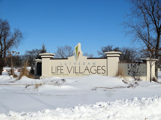 The entrance sign for Life Villages, surrounded by snow in winter.