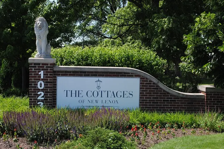 Entrance sign for The Cottages with a lion statue on top.