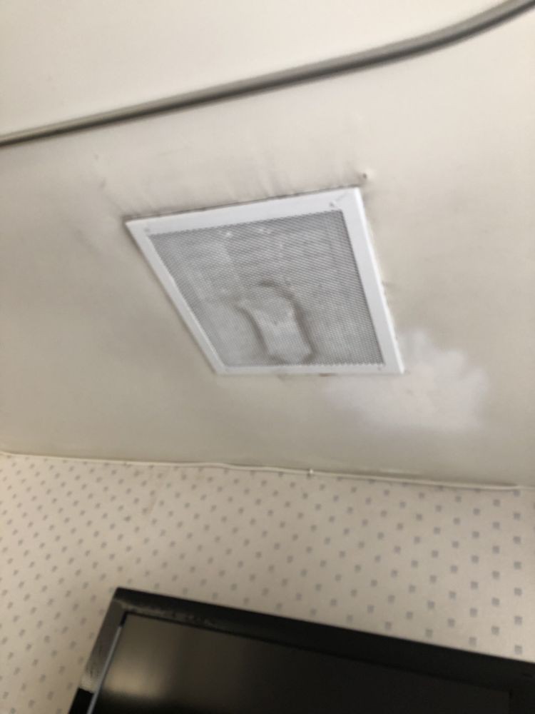 A ceiling vent with visible water damage and discoloration.