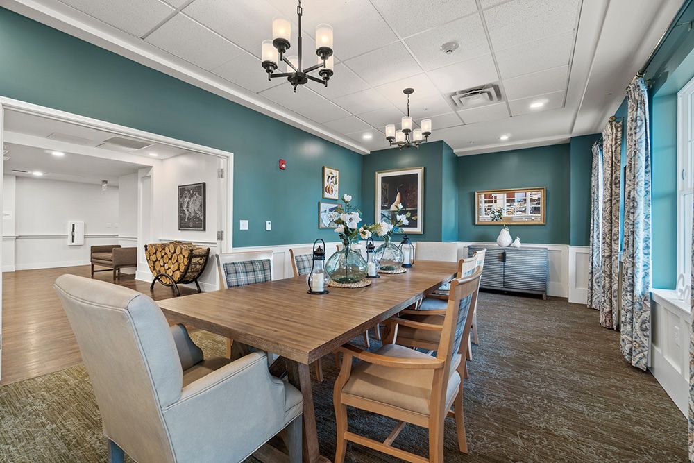 A cozy dining room with a wooden table, cushioned chairs, and elegant lighting.