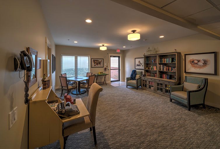 A cozy living room with a seating area, bookshelf, and desk.