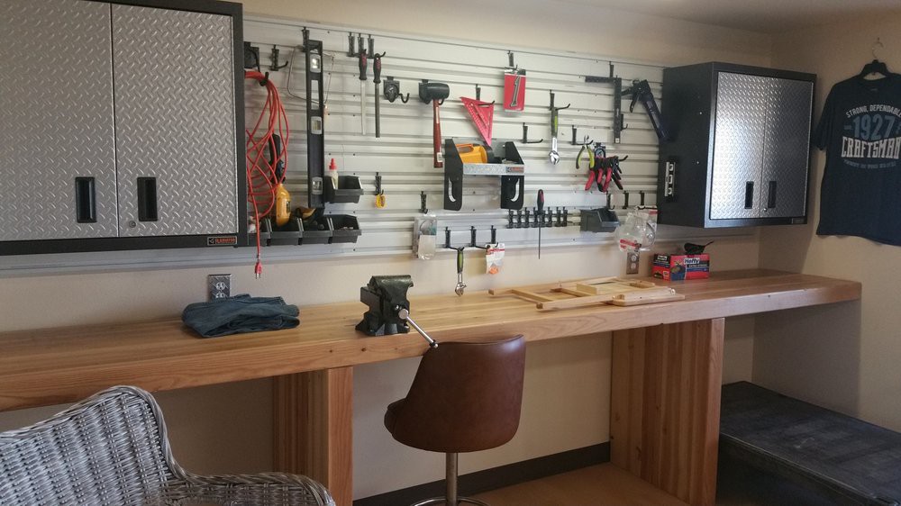 A well-organized workshop with a wooden workbench and various tools neatly arranged on a pegboard.