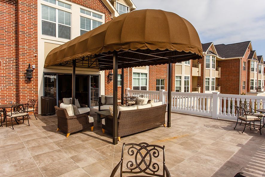 A residential patio with a brown canopy covering a rattan seating area.
