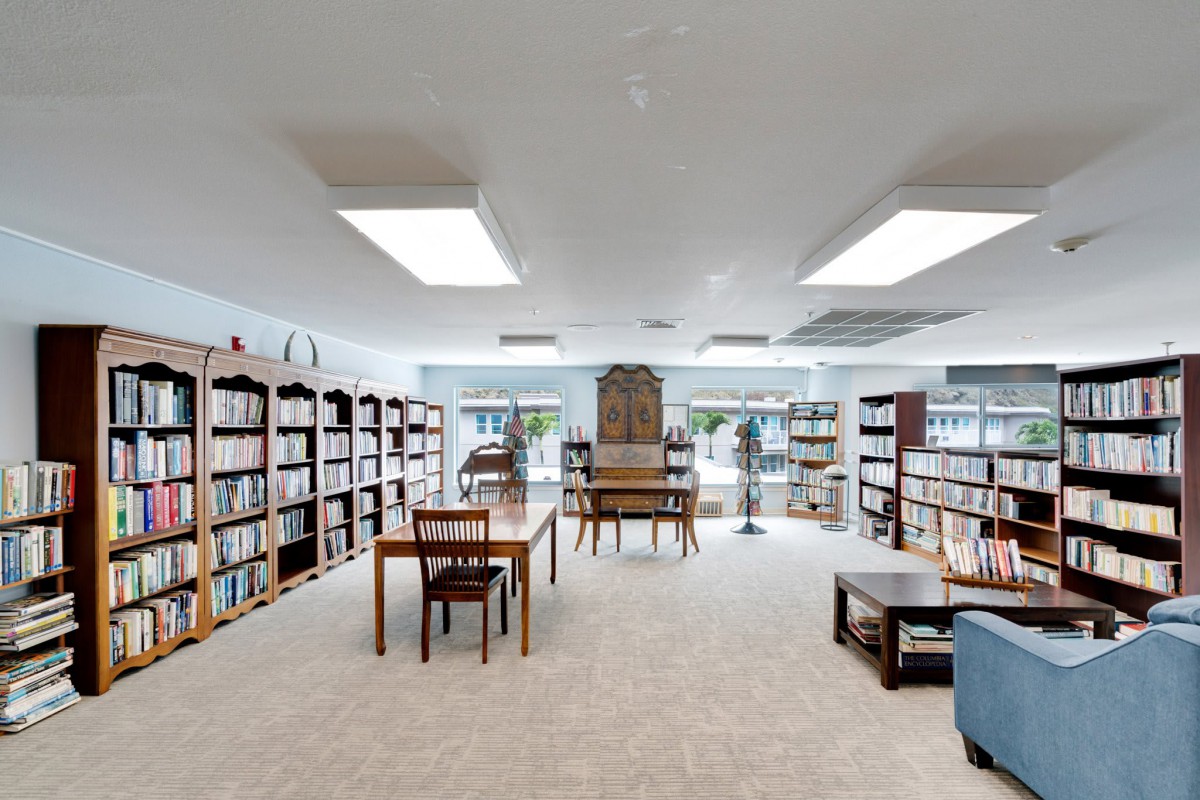 A cozy library with bookshelves and a reading area featuring tables and chairs.
