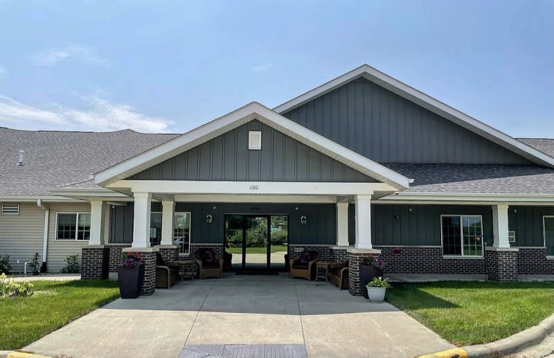 A modern residential building with a prominent entrance and a well-maintained front yard.