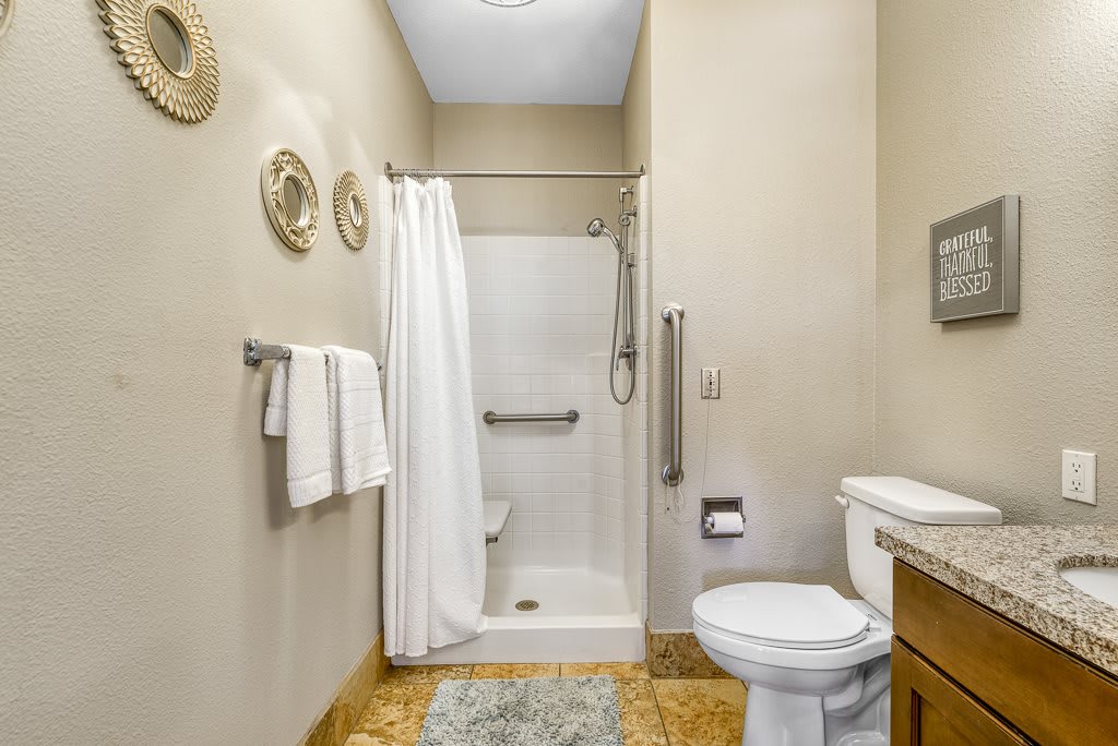 A clean and modern bathroom featuring a shower with a curtain, a toilet, and neatly hung towels.