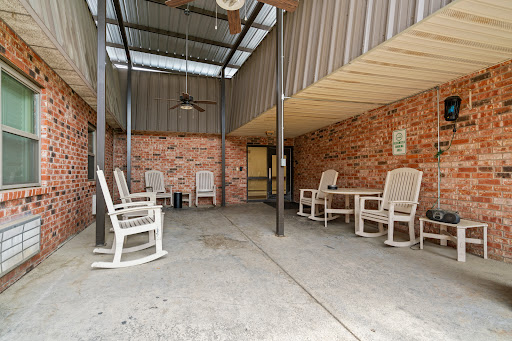 A cozy outdoor patio featuring rocking chairs and a ceiling fan, perfect for relaxation.
