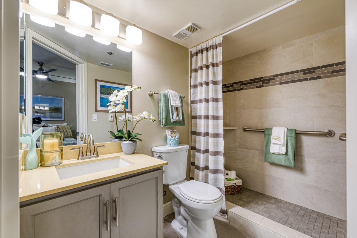 A well-designed bathroom with a shower, sink, and toilet, featuring modern decor and lighting.