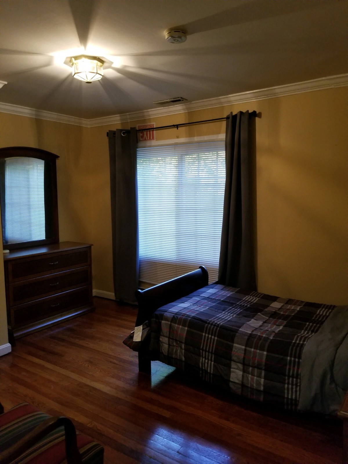 Cozy bedroom with a single bed, dresser, and window with curtains.
