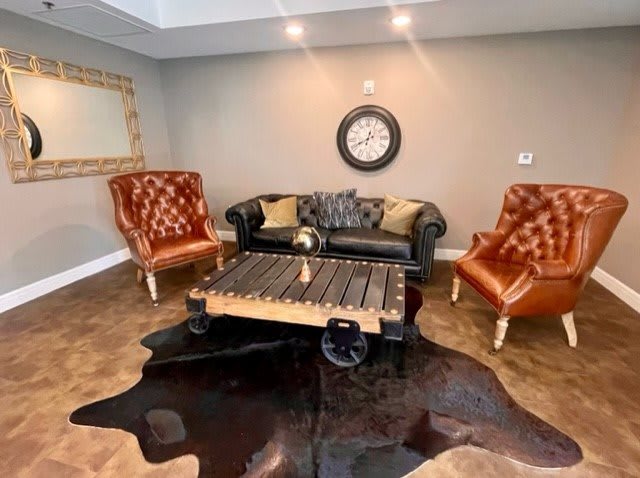 A modern living room with a black sofa, brown leather armchairs, a unique coffee table, and a decorative rug.