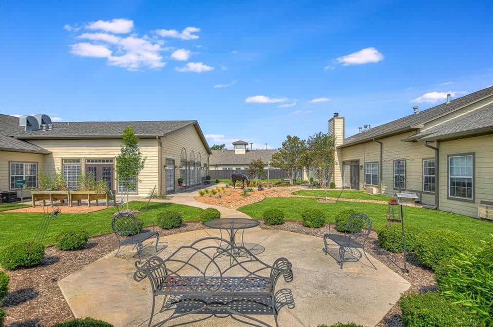 A peaceful courtyard with benches and landscaping between buildings under a clear blue sky.