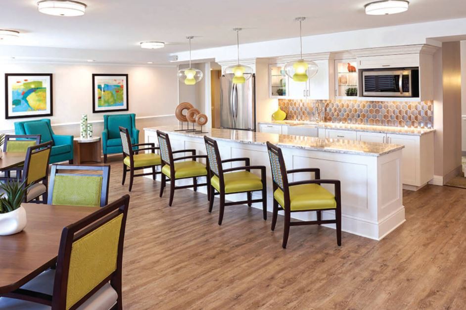 A modern kitchen with white countertops, yellow bar stools, and wood flooring.