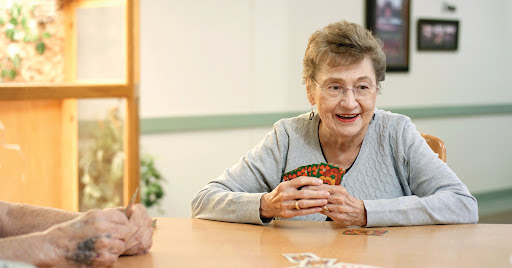 An elderly woman enjoying a card game, smiling warmly as she engages in social interaction.