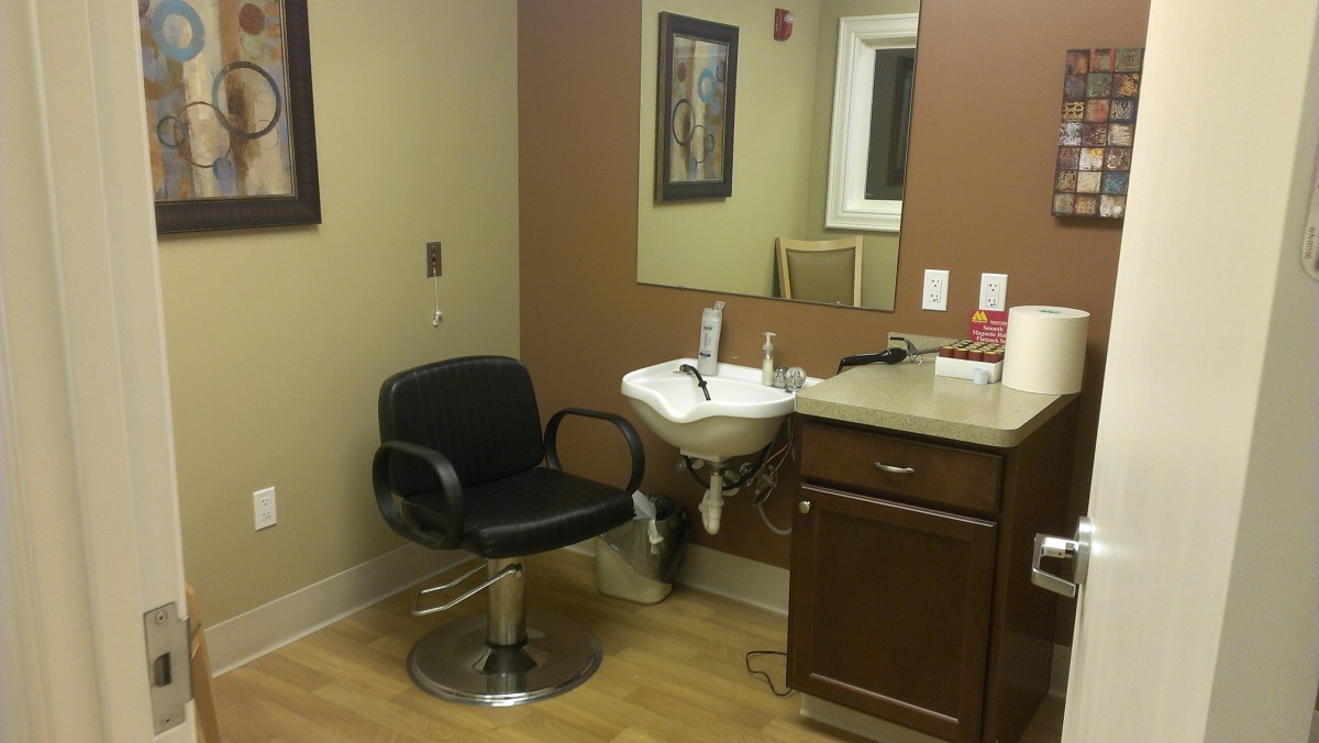A salon setup with a chair, sink, and mirror.