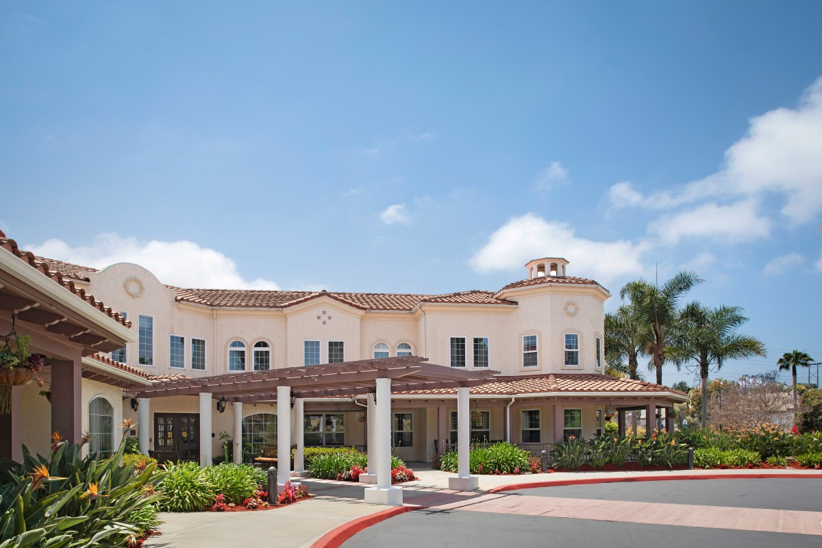 A large residential building with a welcoming entrance and a cloudy sky backdrop.