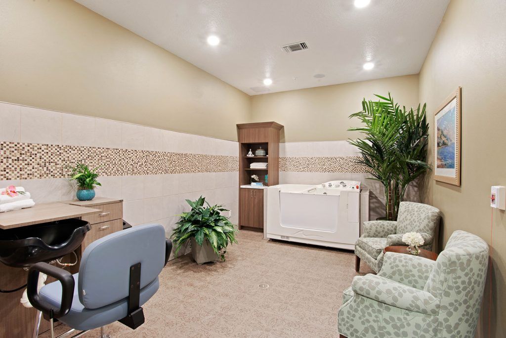 A tranquil spa room featuring a bathtub, comfortable seating, and lush plants.