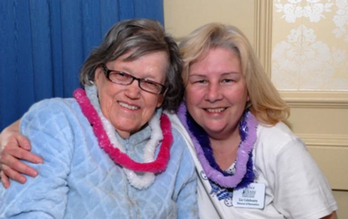 Two smiling women wearing colorful leis.