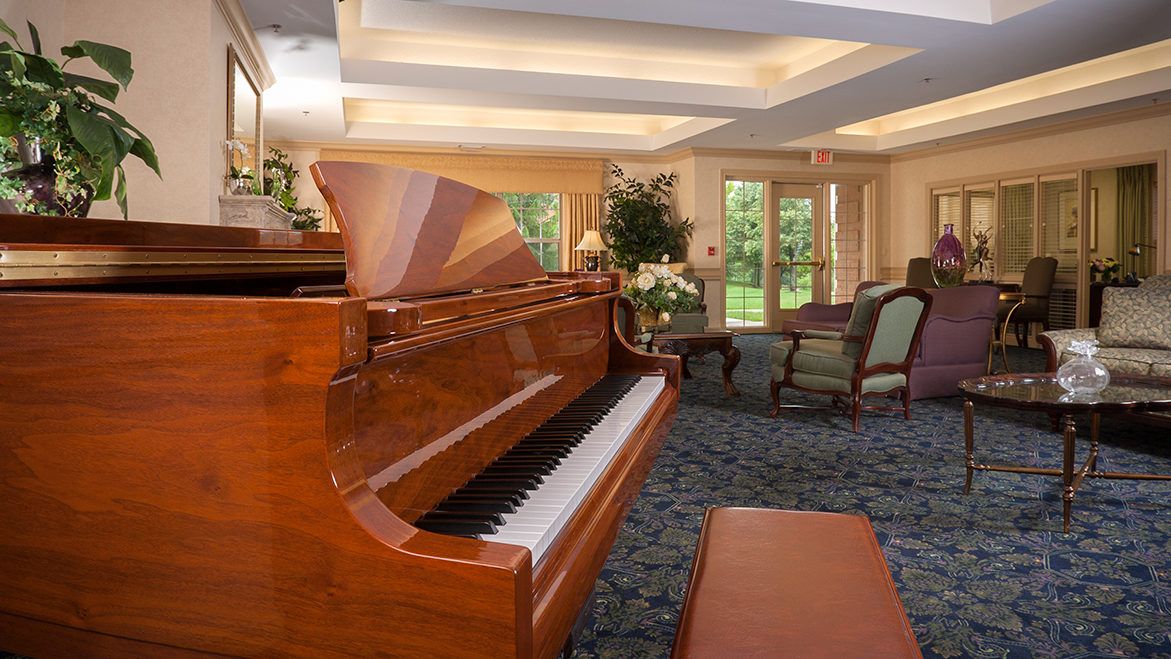 A cozy living room featuring a polished grand piano and ample natural light.