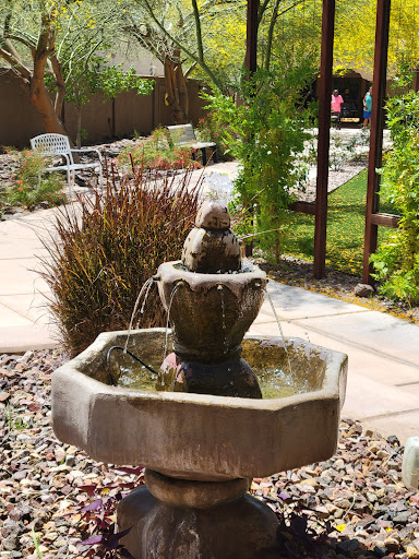 A serene fountain surrounded by lush greenery in a sunny garden.