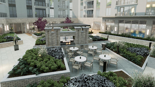 A serene outdoor garden space featuring modern seating arrangements and greenery in an apartment complex.