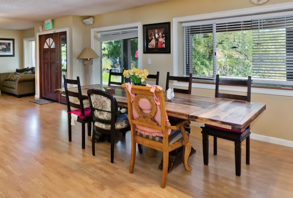 A cozy dining room with a large wooden table and an eclectic mix of chairs.