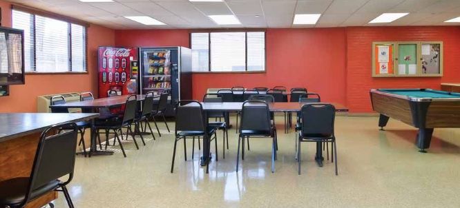 An empty break room with tables, chairs, and a vending machine.