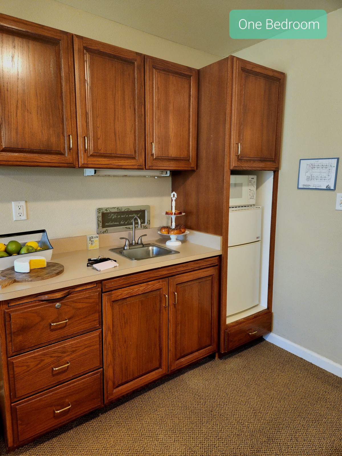 A compact kitchen with wooden cabinets, a sink, and a built-in fridge.