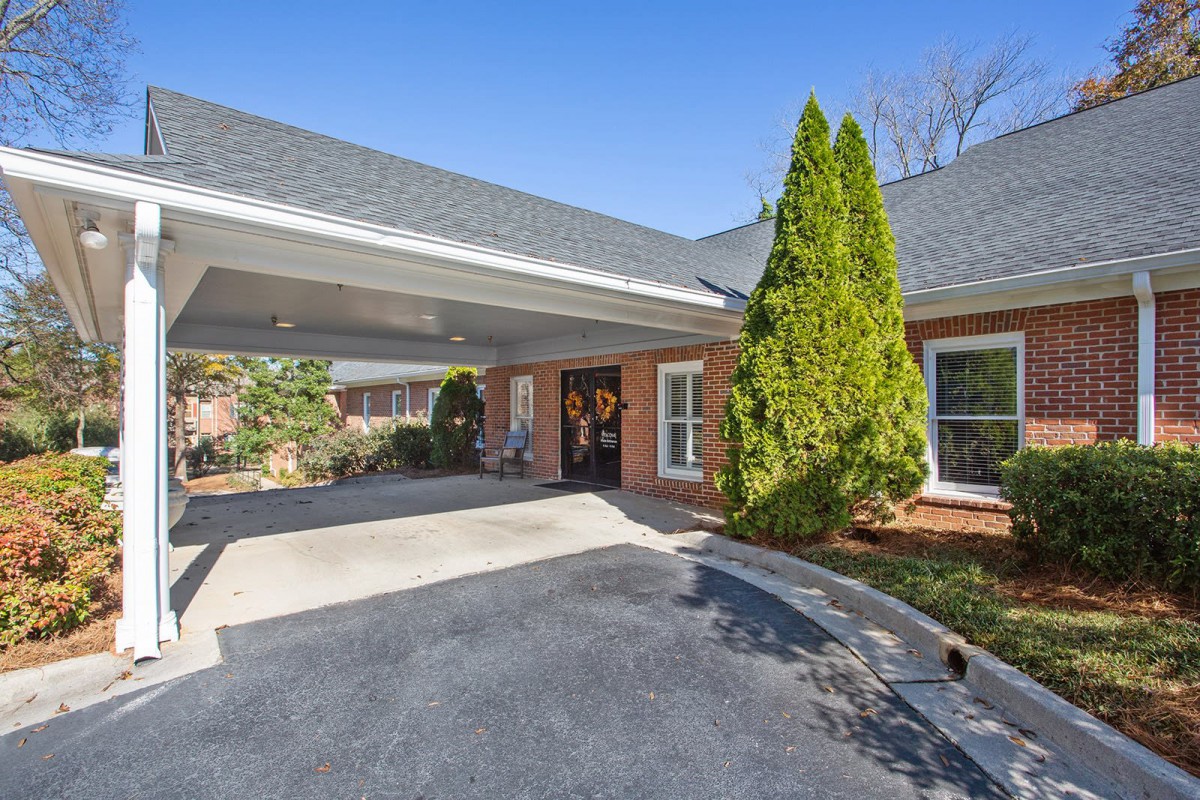 A brick house with a covered driveway and well-maintained landscaping.