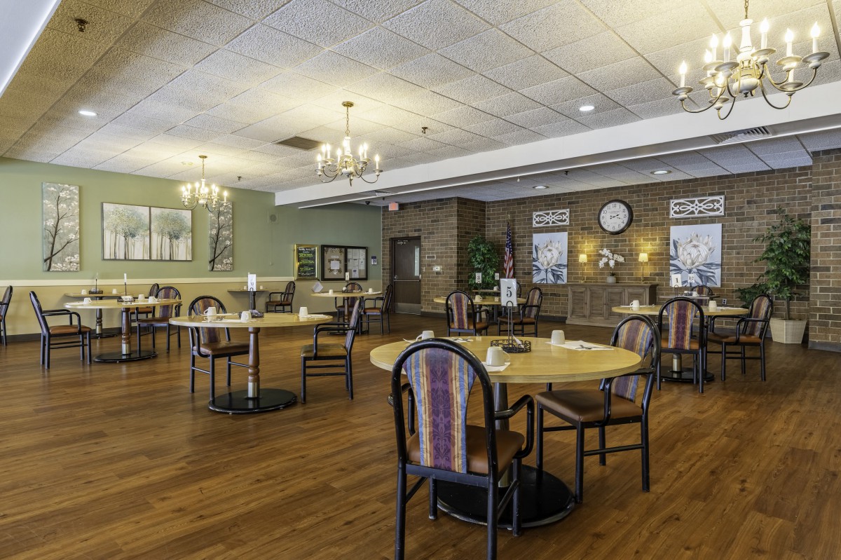 A cozy dining area with round tables and chandeliers, featuring a warm and inviting ambiance.