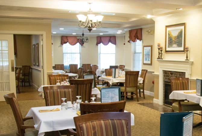 A cozy restaurant dining area with neatly arranged tables and chairs, featuring elegant decor and a chandelier.