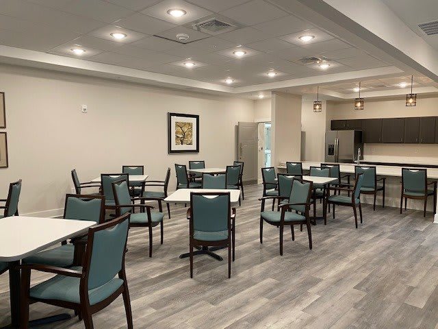 A modern and spacious dining room with multiple tables and chairs, well-lit and featuring elegant flooring.