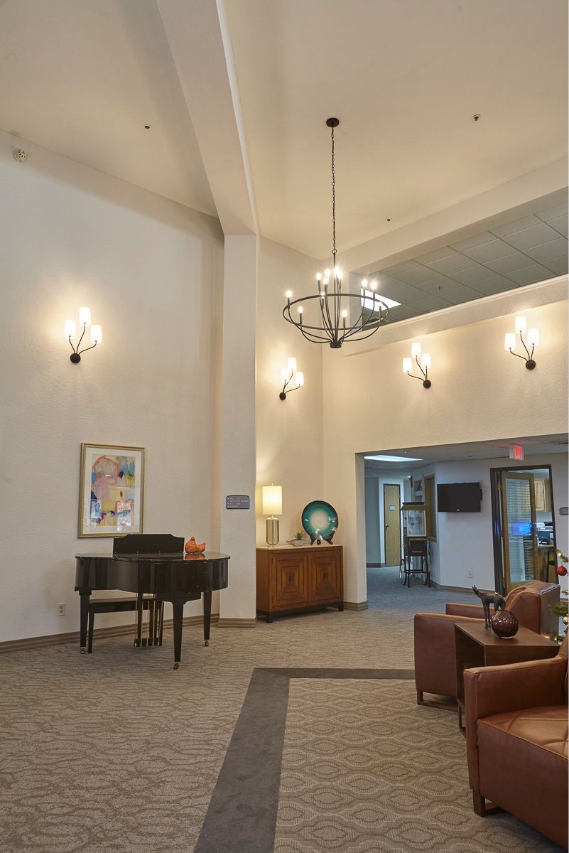 A spacious lobby with a piano, elegant lighting fixtures, and comfortable seating.